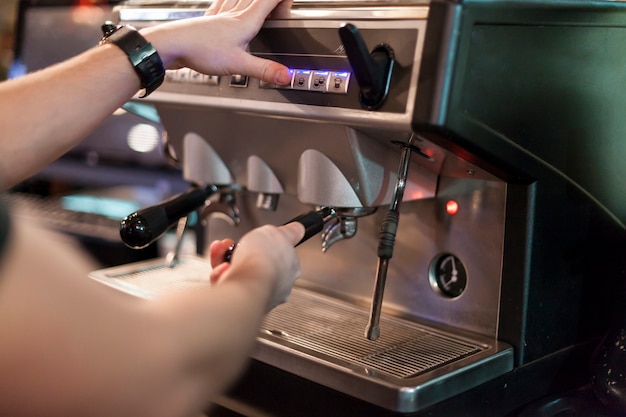 Hombre de cultivos usando la máquina de café en la cafetería