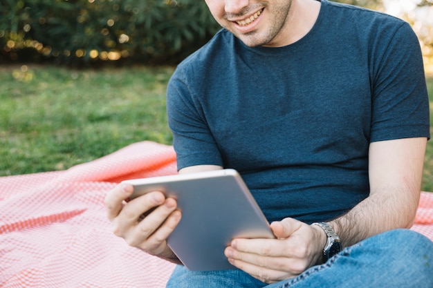 Hombre de cultivos usando tableta en picnic