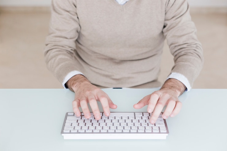 Foto gratuito hombre de cultivos usando el teclado de la computadora
