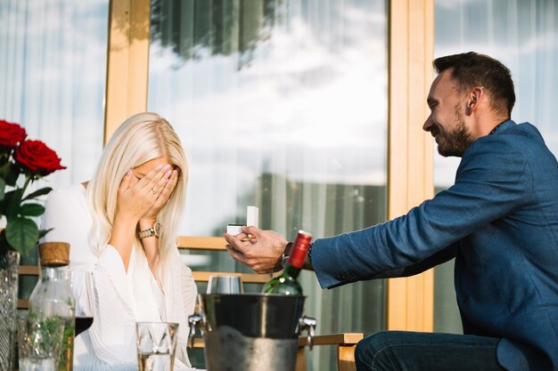 Hombre dando anillo de compromiso a su novia tímida