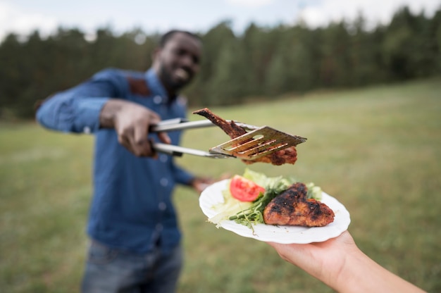 Hombre dando bistec a persona para barbacoa