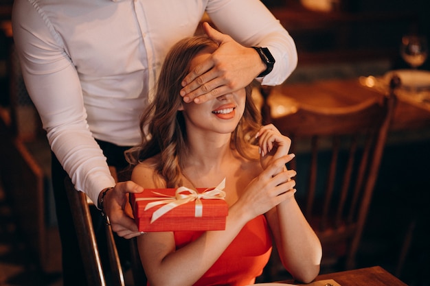Hombre dando una caja de regalo en el día de San Valentín en un restaurante.