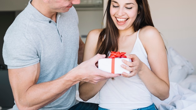 Hombre dando caja de regalo a mujer joven