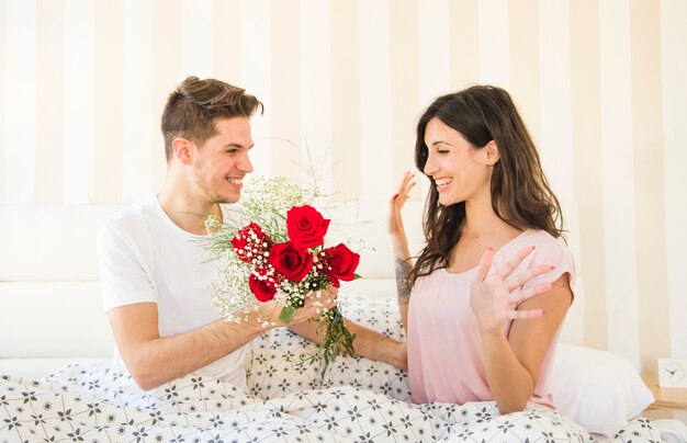 Hombre dando flores a la mujer en la cama