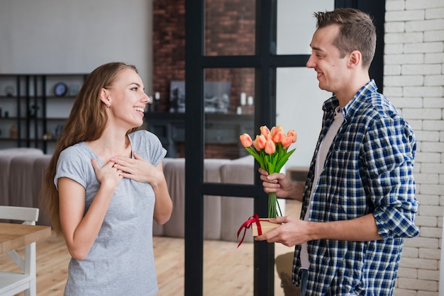 Hombre dando flores y regalo a su esposa.