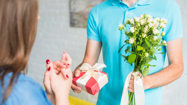 Hombre dando flores y regalos de San Valentín a su esposa