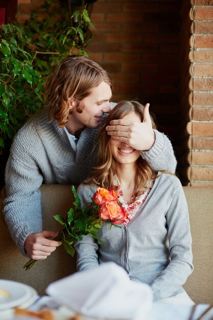 Hombre dando un ramo de flores y un beso a su esposa