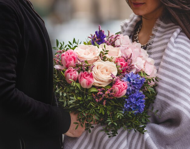 Hombre dando un ramo de flores mixtas a una mujer