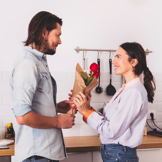 Foto gratuita hombre dando ramo de rosas rojas a mujer en cocina