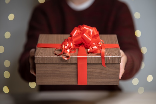 Hombre dando un regalo de Navidad decorado con cinta roja