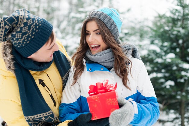 Hombre dando regalo rojo a su novia en invierno