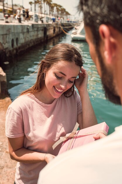 Hombre dando regalos a su novia sonriente en el puerto