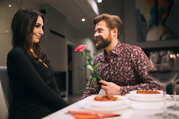 Hombre dando rosa a chica en café