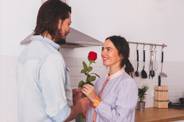 Hombre dando rosa roja a mujer en cocina