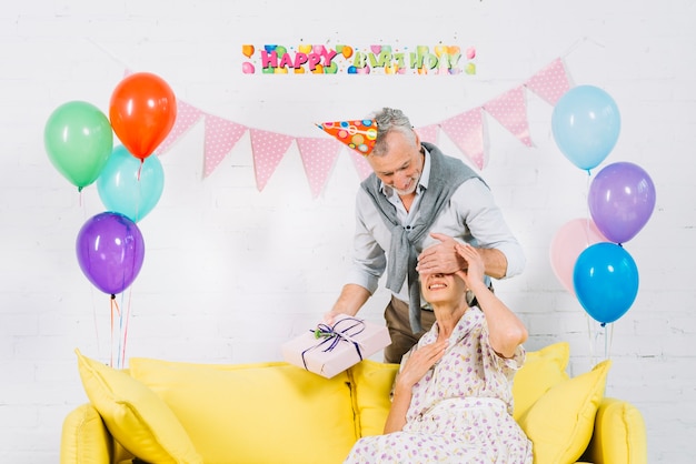 Hombre dando sorpresa regalo de cumpleaños a su esposa