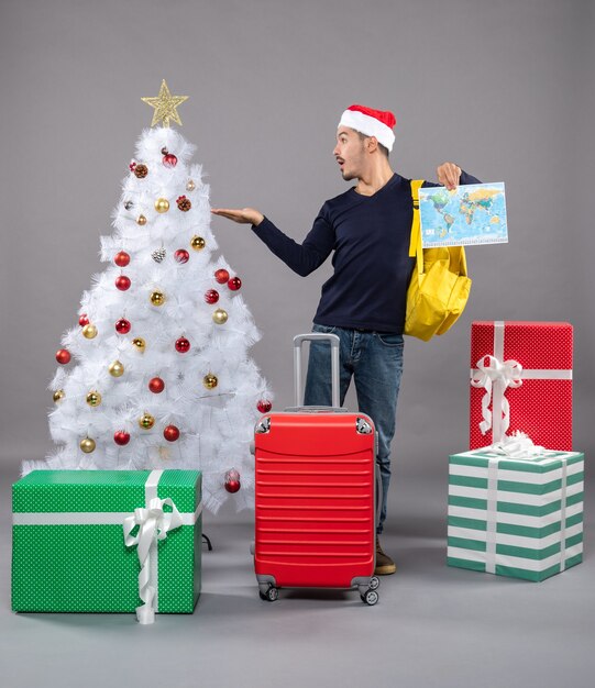 Hombre con el dedo índice del mapa que muestra el árbol de Navidad en gris aislado