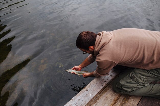 Hombre dejando pescado recién pescado en el lago