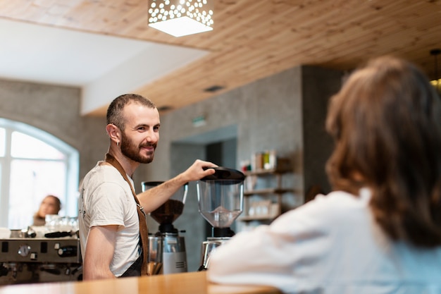 Hombre en delantal sonriendo y haciendo café