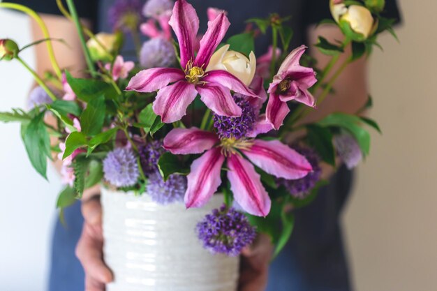 Foto gratuita un hombre en un delantal sostiene un jarrón de flores de cerca