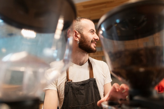 Hombre con delantal trabajando y porta café desenfocado