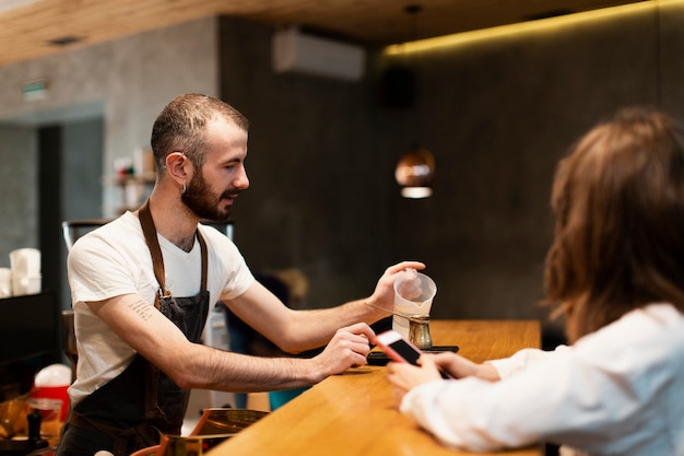 Hombre con delantal vertiendo agua en cafetera