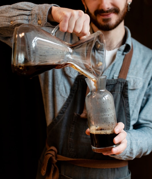 Hombre con delantal vertiendo café en frasco