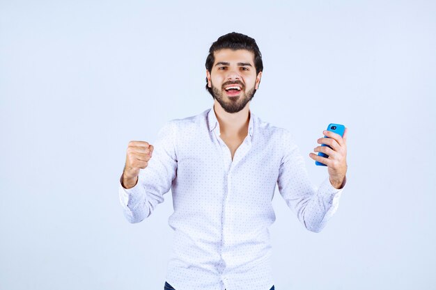 Hombre demostrando su nuevo modelo de teléfono inteligente y sintiéndose satisfecho