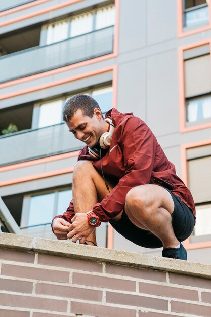 Hombre deportivo atando zapatos en entorno urbano