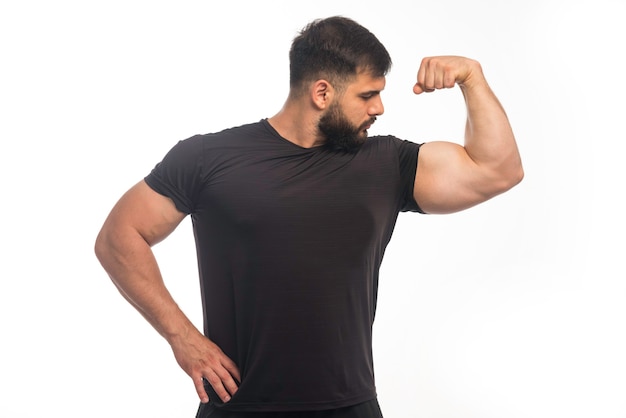 Foto gratuita hombre deportivo en camisa negra mostrando los músculos de su brazo