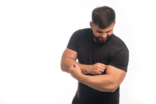 Hombre deportivo en camisa negra mostrando sus bíceps