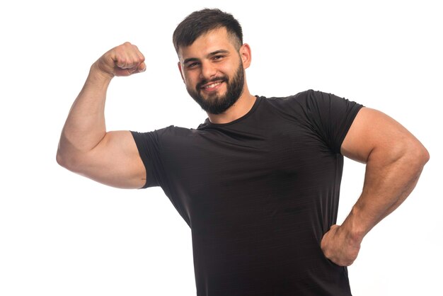 Hombre deportivo con camisa negra sintiéndose fuerte