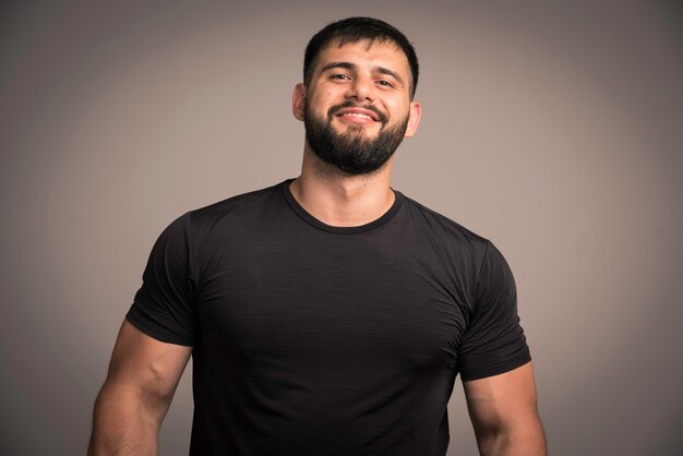 El hombre deportivo con camisa negra se ve confiado y sonriente.