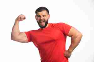 Foto gratuita hombre deportivo con camisa roja mostrando los músculos del brazo y gritando.