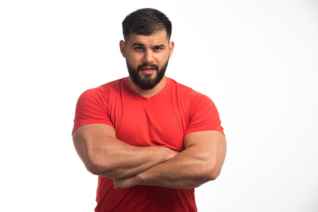 Hombre deportivo en camisa roja que demuestra sus músculos superiores.