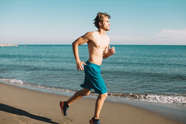 Hombre deportivo corriendo en la playa