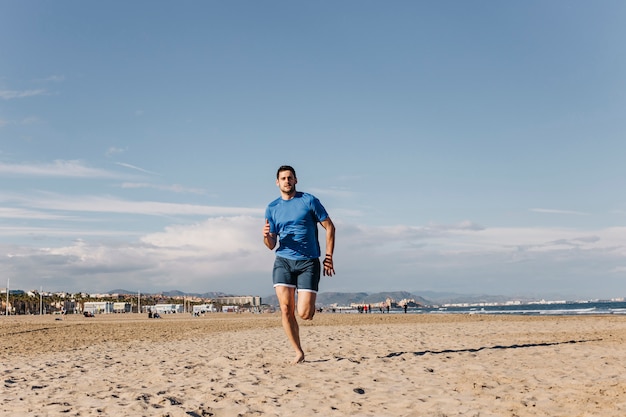 Hombre deportivo corriendo en la playa