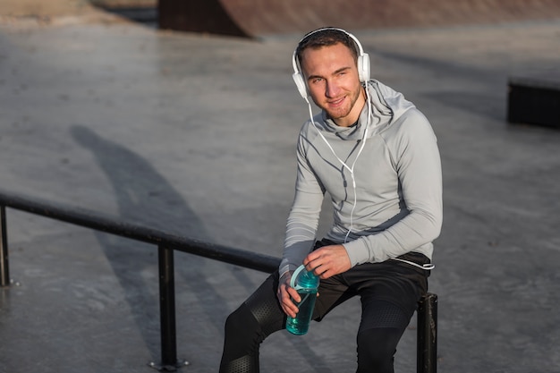 Foto gratuita hombre deportivo escuchando música y sosteniendo una botella de agua