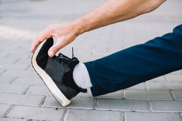 Hombre deportivo estirando su pie en el callejón