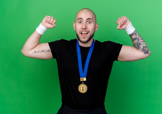 Foto gratuita hombre deportivo joven alegre con pulsera y medalla haciendo un gesto fuerte