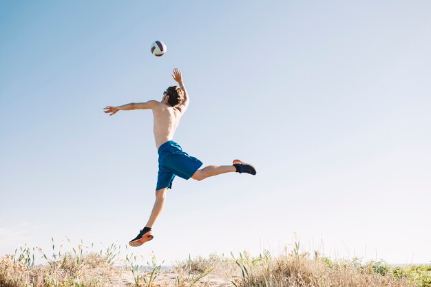 Hombre deportivo saltando por balonvolea