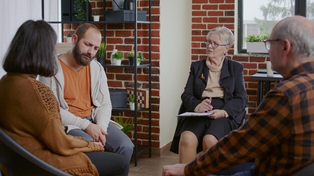 Hombre con depresión confesándose en una reunión de terapia con alcohólicos. Persona que cuenta una historia de adicción para recibir ayuda y consejos de un terapeuta en un grupo de rehabilitación de apoyo.