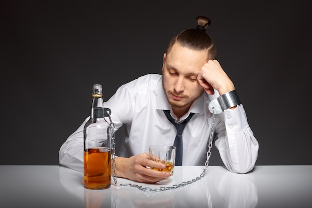 Hombre deprimido pasando el tiempo con una botella de whisky