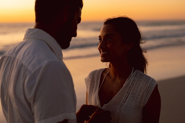 Hombre desabrochando la parte superior de la mujer en la playa