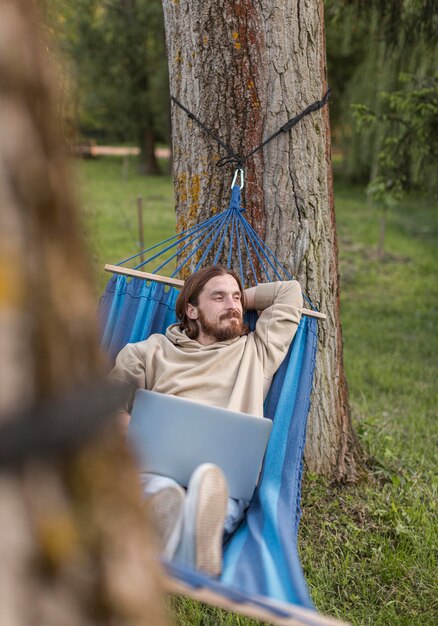 Hombre descansando en una hamaca con laptop