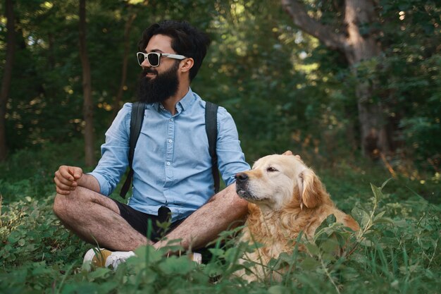 Hombre descansando sobre la hierba sentado piernas cruzadas con su perro