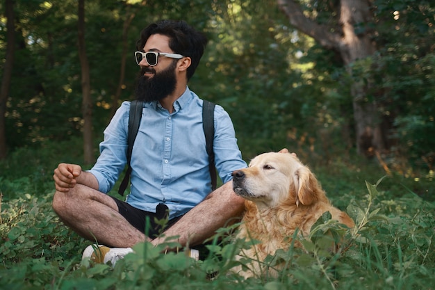 Hombre descansando sobre la hierba sentado piernas cruzadas con su perro