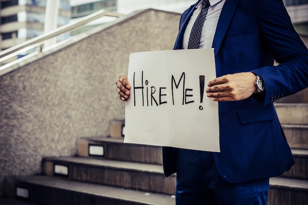 Hombre desempleado buscando desesperadamente un trabajo. Sosteniendo una necesidad de un signo de trabajo.