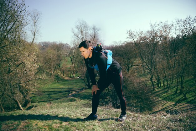 Hombre después de correr en un parque o bosque contra el espacio de árboles