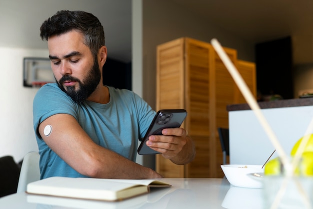 Foto gratuita hombre diabético comprobando el sensor de parche de glucosa