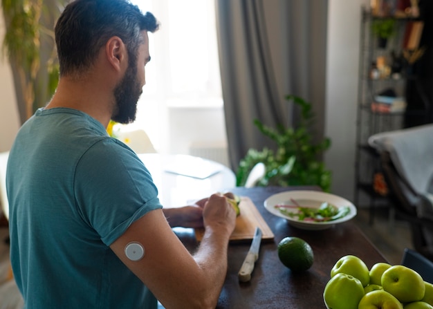 Foto gratuita hombre diabético con sensor de parche de glucosa preparando una comida